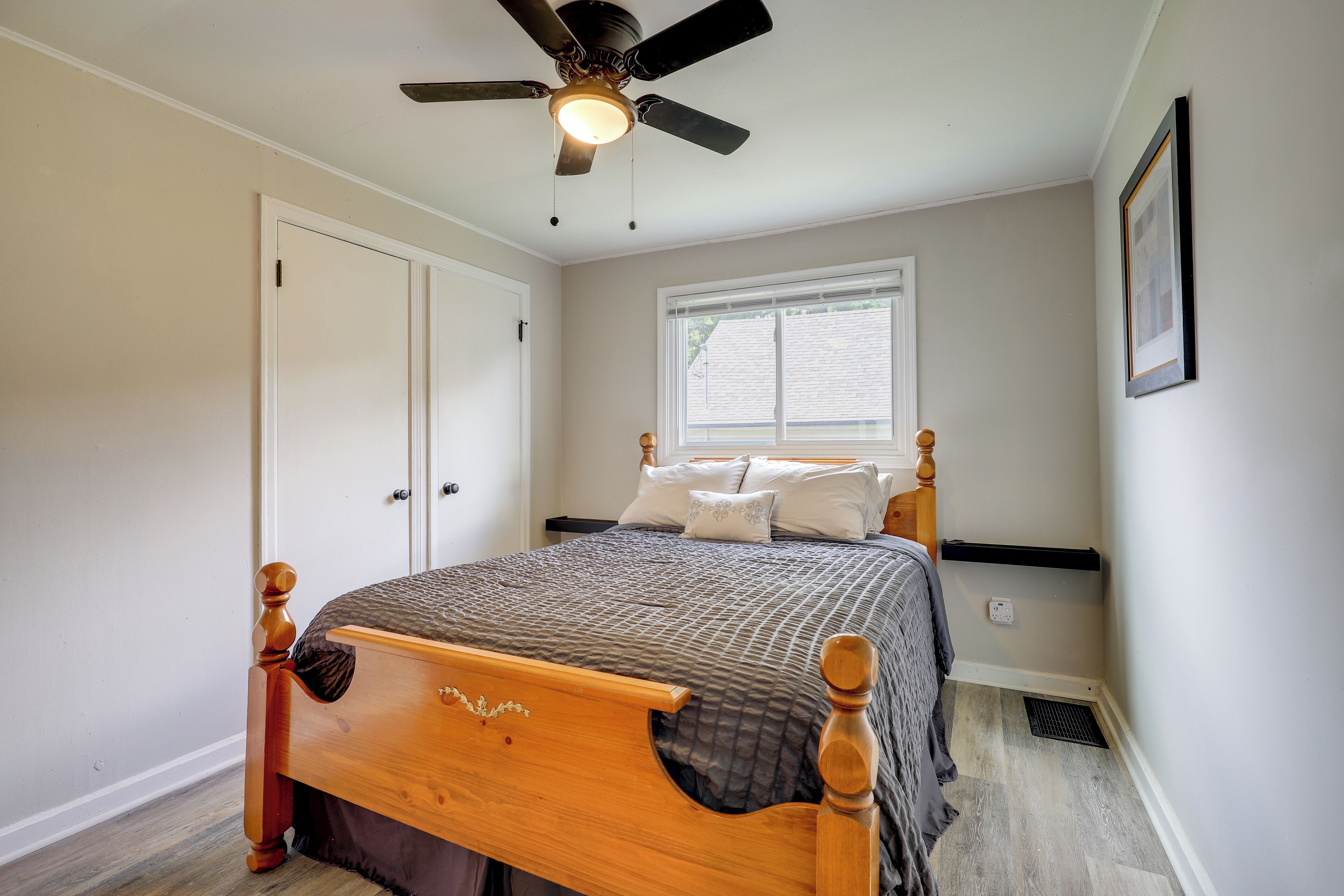 A bedroom with a wooden bed, a ceiling fan, a window, and a door.