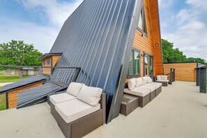 A modern outdoor seating area with a sloped roof, built-in benches, and a view of a wooden house. - A Frame Family Escape With Water Views (Little Elm)