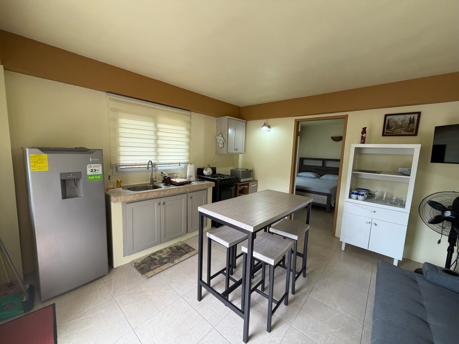 A compact kitchen with a refrigerator, sink, stove, and dining area.