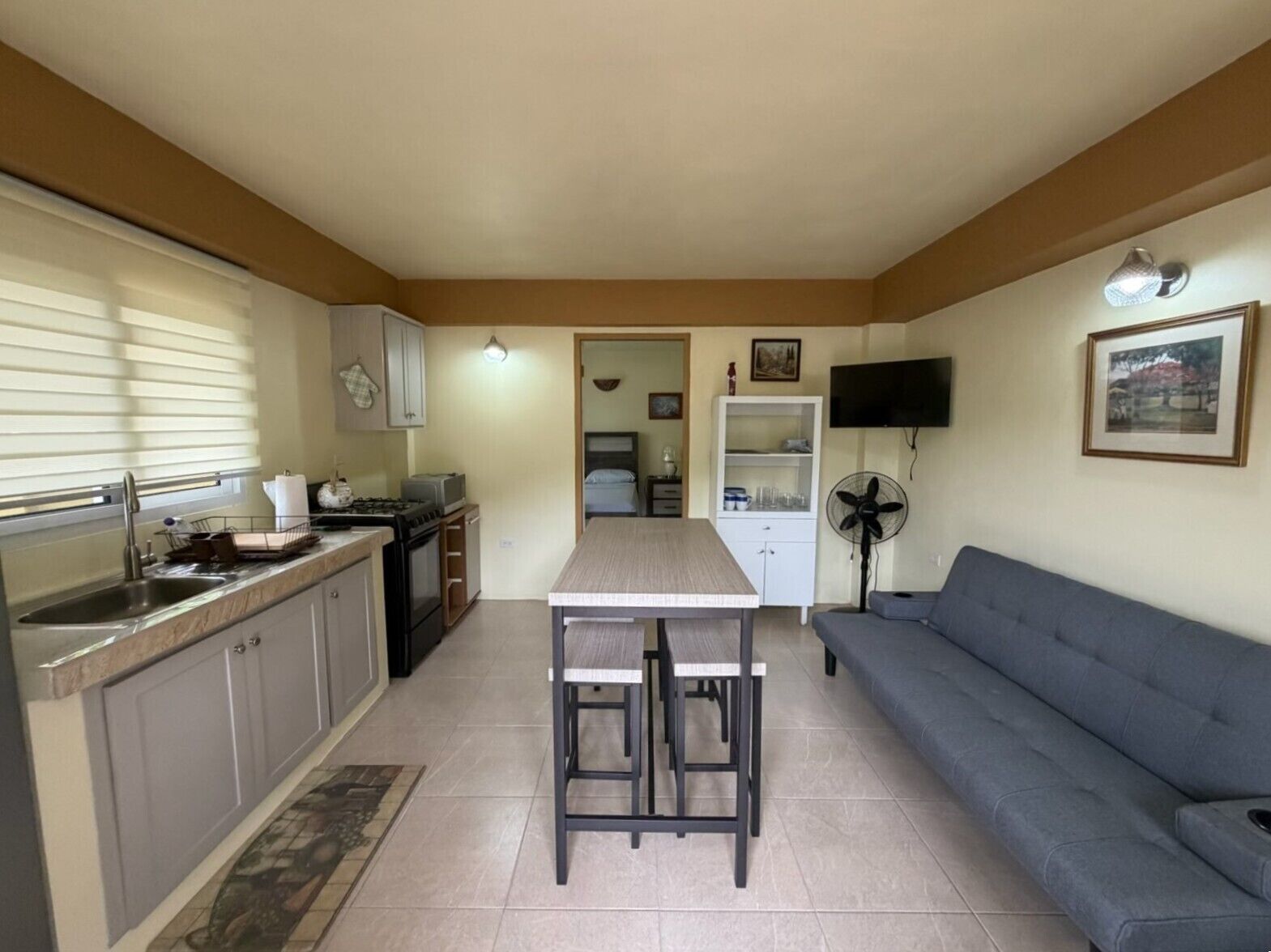 A compact living space with a kitchenette, dining area, and a sofa.
