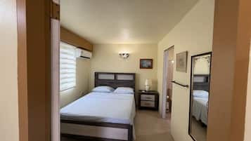 A bedroom with a bed, bedside table, lamp, and a mirror.