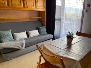 Ein Zimmer mit einer Couch, einem Esstisch und einem Fenster mit Blick.