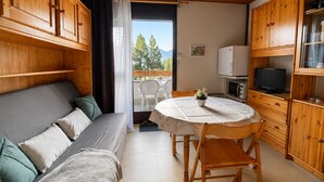 A cozy room with a sofa, a dining table, and wooden cabinets. - Bright studio with mountain view for 4 people (Morillon)