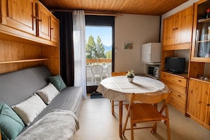 Ein gemütliches Zimmer mit einer Couch, einem Esstisch und Holzschränken.
