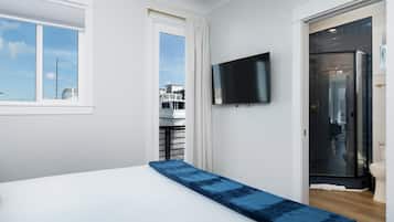 Ein Schlafzimmer mit einem Bett, einem an der Wand montierten Fernseher und Blick auf Boote durch ein Fenster.