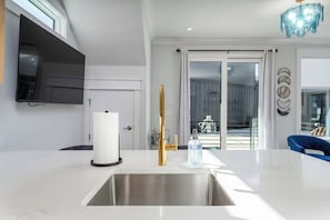 Eine moderne Küche mit einer Edelstahl-Spüle, einem goldenen Wasserhahn und einer weißen Marmorarbeitsplatte.