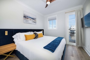 Ein Hotelzimmer mit Bett, einem Gemälde, einem Fenster, einem Fernseher und Blick auf ein Boot vor dem Haus.