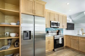Une cuisine moderne dotée d’appareils électroménagers en acier inoxydable, de meubles en bois et d’un dosseret carrelé.