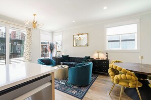 Un salon moderne avec un canapé, des fauteuils, une table à manger et une grande fenêtre.