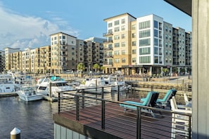 A marina with boats docked, a waterfront promenade, and modern apartment buildings in the background.