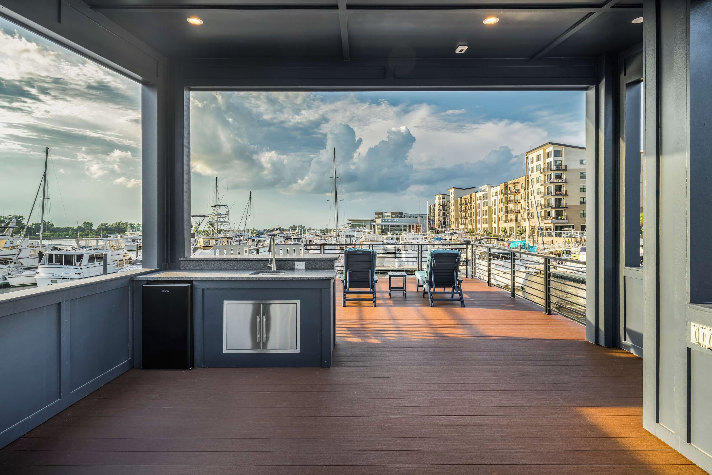 Una terraza moderna al aire libre con vistas a un puerto deportivo y edificios.