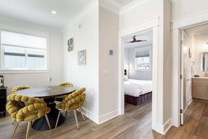 A modern hotel room with a bed, bedside table, and a bathroom with a mirror and towel rack.