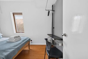 Ein Schlafzimmer mit einem Bett, einem Schreibtisch, einem Stuhl, einem Fenster und einer Tür.