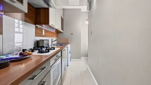 A modern kitchen with a wooden countertop, stainless steel appliances, and a built-in oven. - 1-bed Flat - Fitzrovia - Sleeps 2 (London)