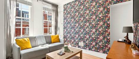 Un salon avec un canapé, une table et un papier peint à motifs floraux.