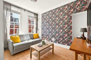 Ein Wohnzimmer mit einer Couch, einem Tisch und floralem Wandpapier.