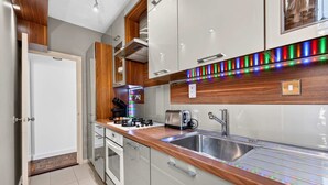 A modern kitchen with a stainless steel sink, wooden countertop, and a colorful LED light strip. - 1-bed Flat - Fitzrovia - Sleeps 2 (London)