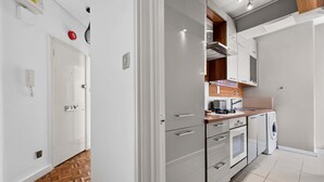 A modern kitchen with white cabinetry, a built-in oven, and a washing machine. - 1-bed Flat - Fitzrovia - Sleeps 2 (London)