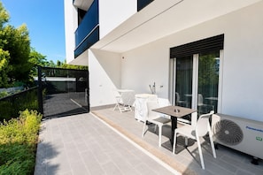 Eine moderne Außenpatio mit Tisch und Stühlen, einer Panasonic Klimaanlage und einer Glastür, die auf einen Balkon führt.