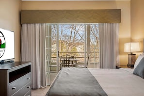 A hotel room with a bed, a TV, a desk, a lamp, and a balcony with a table and chairs. - Branson Condo near Shows, Golf + Hwy 76 Strip (Branson)