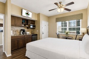 Ein Hotelzimmer mit Bett, einer Küchenzeile, einem Deckenventilator, einem Fenster mit Blick und einer Tür.