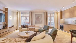 A modern living room with a sofa, armchairs, a coffee table, and a kitchen area. - THE ESSENCE OF PARISIAN ELEGANCE ,JUST MOMENTS FROM THE ICONIC ARC DE TRIOMPHE (Paris)