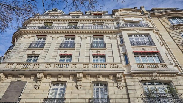 Um edifício de vários andares com arquitetura clássica, com varandas ornamentadas e grandes janelas.