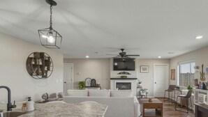 Una cocina moderna con una isla de mármol, un comedor con mesa de madera y una sala de estar con sofá.