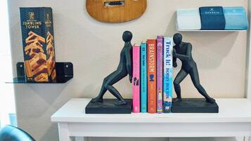 A white shelf with two figurines, a guitar, and books.