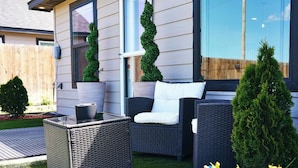 Un patio con muebles de mimbre, una mesa pequeña y plantas en macetas.