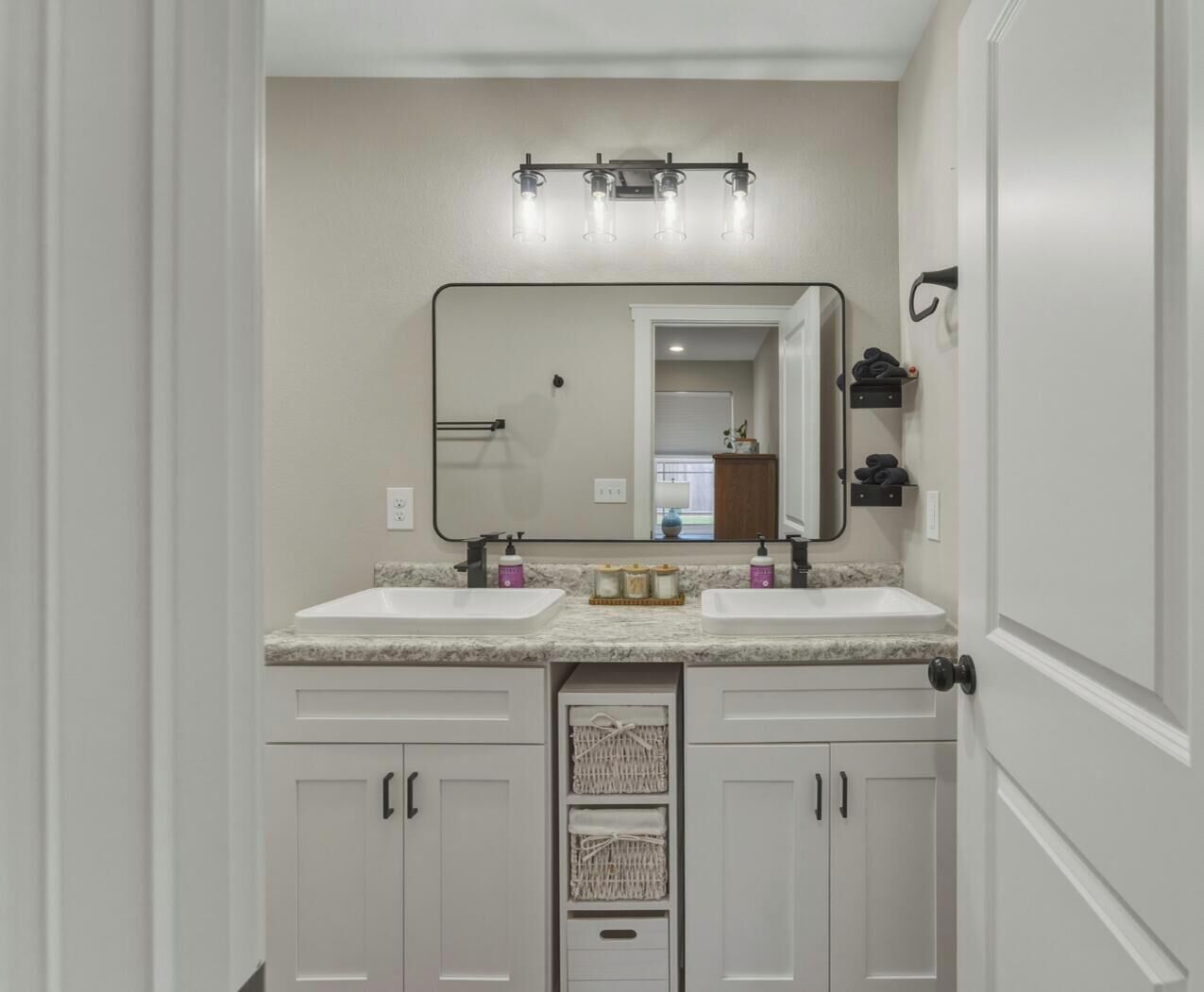A bathroom with two sinks, a large mirror, and a towel rack.