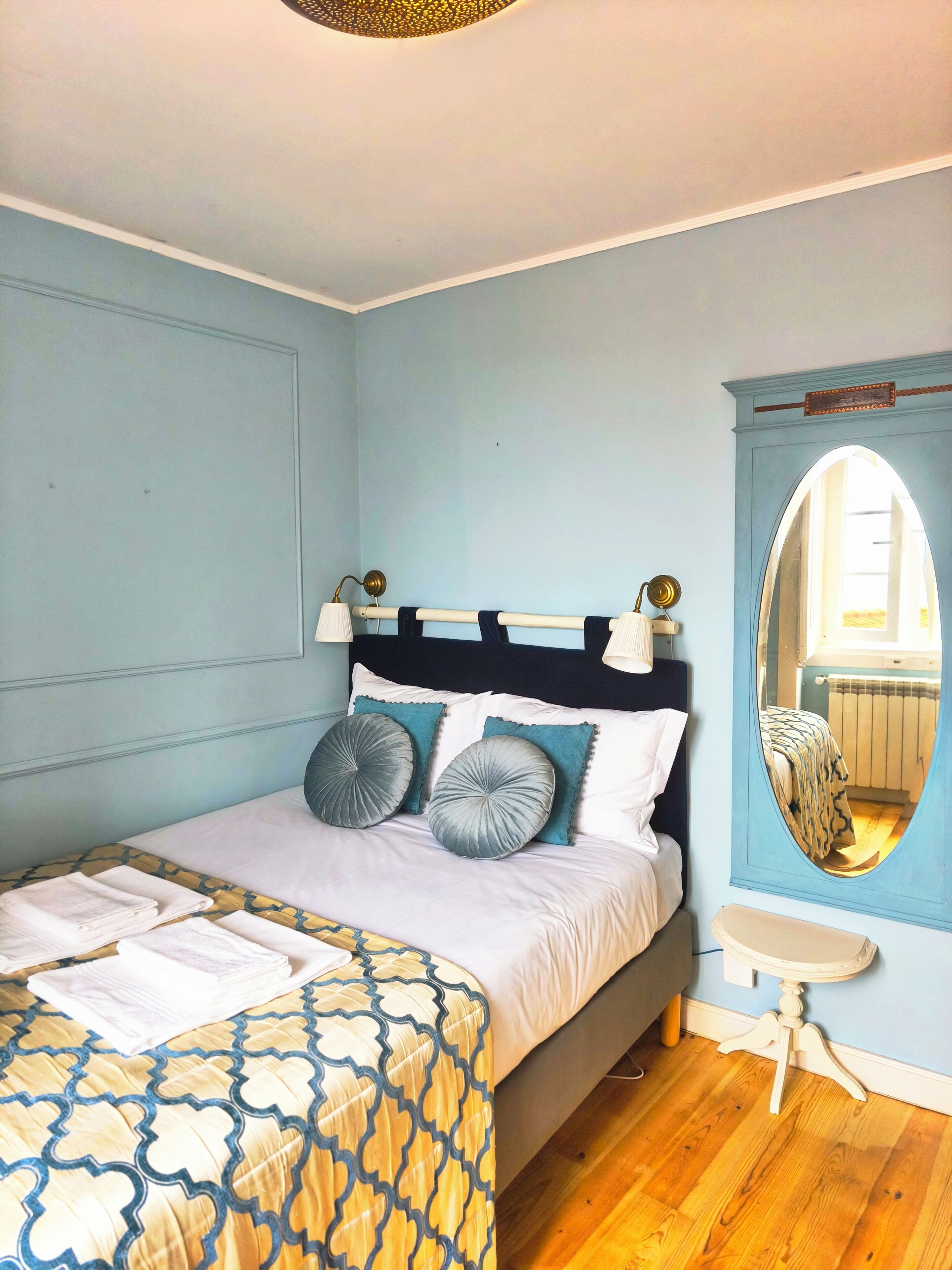 Une chambre à coucher avec un lit, une table de chevet, un miroir et une fenêtre.