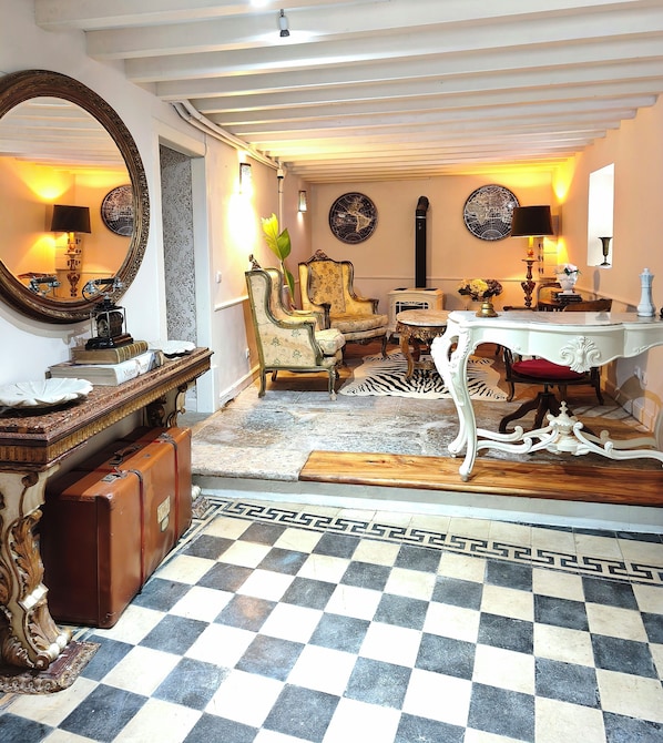 Um quarto com chão quadriculado, um espelho, uma mesa e uma cadeira.