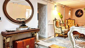 Un piso a cuadros, un espejo redondo, una mesa de estilo antiguo y una pared con diseño.