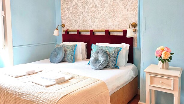 Un dormitorio con una cama, mesitas de noche y una mesita auxiliar con un florero.