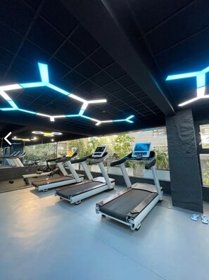 A gym with treadmills, exercise equipment, and a modern ceiling design. - 2-bedroom apartment in lavington Nairobi. With swimming pool and gym. Near malls (Nairobi)