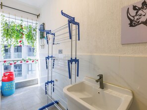 Ein Badezimmer mit einem weißen Waschbecken, einem blauen Wäscheständer und einer roten Mülltonne.
