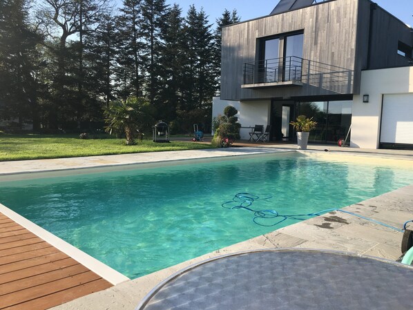 A modern house with a swimming pool, a deck, and a patio area with outdoor furniture. - Quiet Villa with Pool - Saint Nolff (Saint-Nolff)