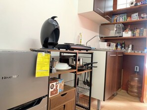 Eine kleine Küche mit einem Hisense Kühlschrank, einem schwarzen Wasserkocher, einer Mikrowelle und einem Wasserspender.