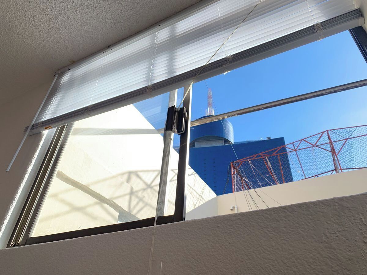 A window with a view of a blue building and a red structure.