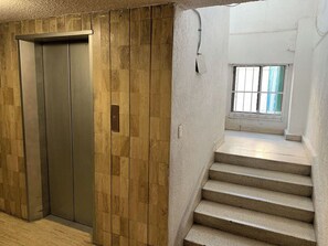 Ein Aufzug, eine Treppe und ein Fenster mit Gitterstäben.
