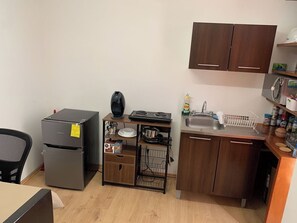 Eine kleine Küche mit Kühlschrank, Herd, Spüle und Holzschränken.
