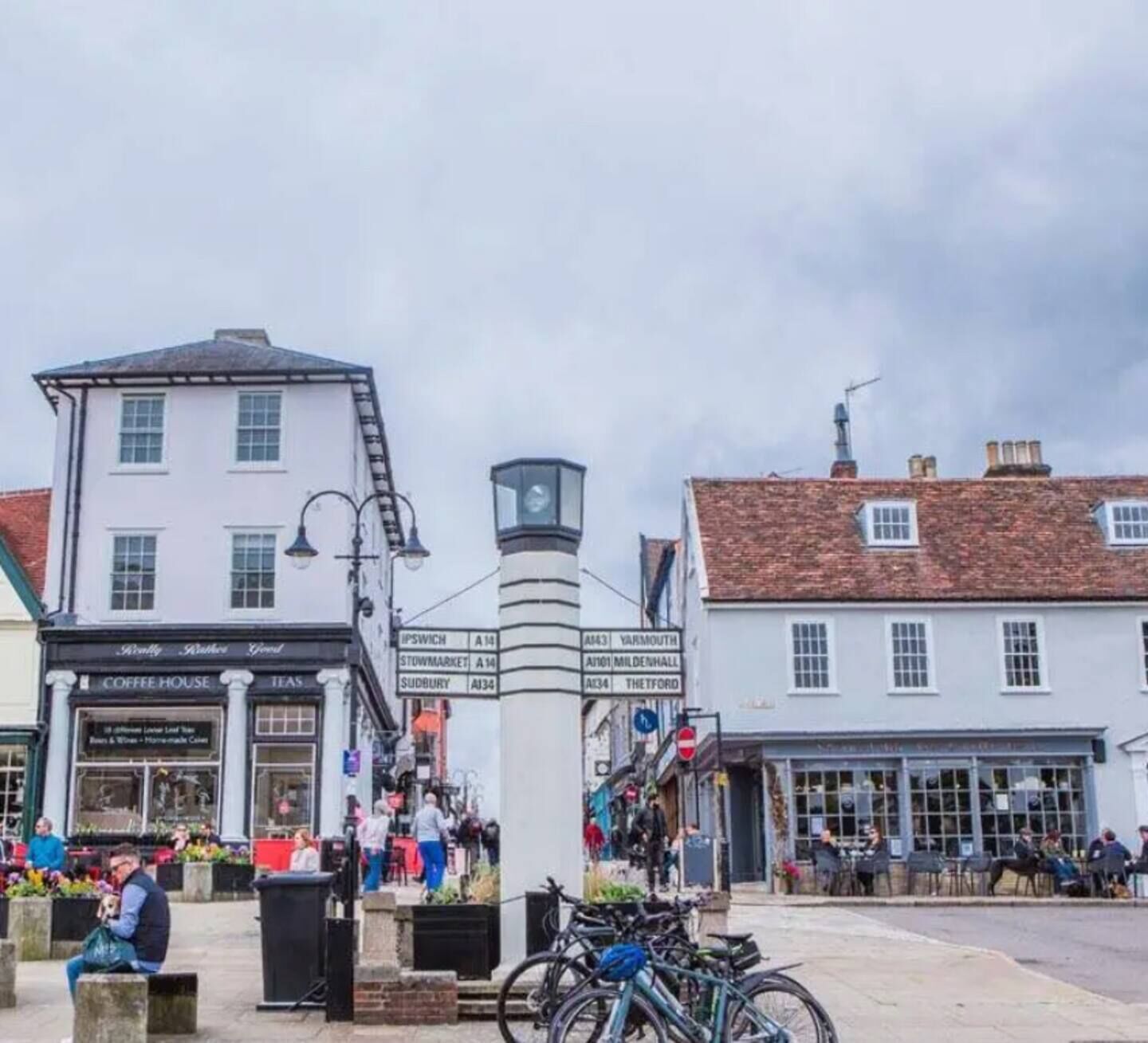 Ein Stadtplatz mit einem Café, einem Glockenturm und einer Kneipe.