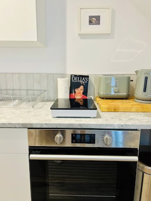 Eine Küche mit einem Edelstahlbackofen, einem Toaster und einem Kochbuch auf der Arbeitsplatte.
