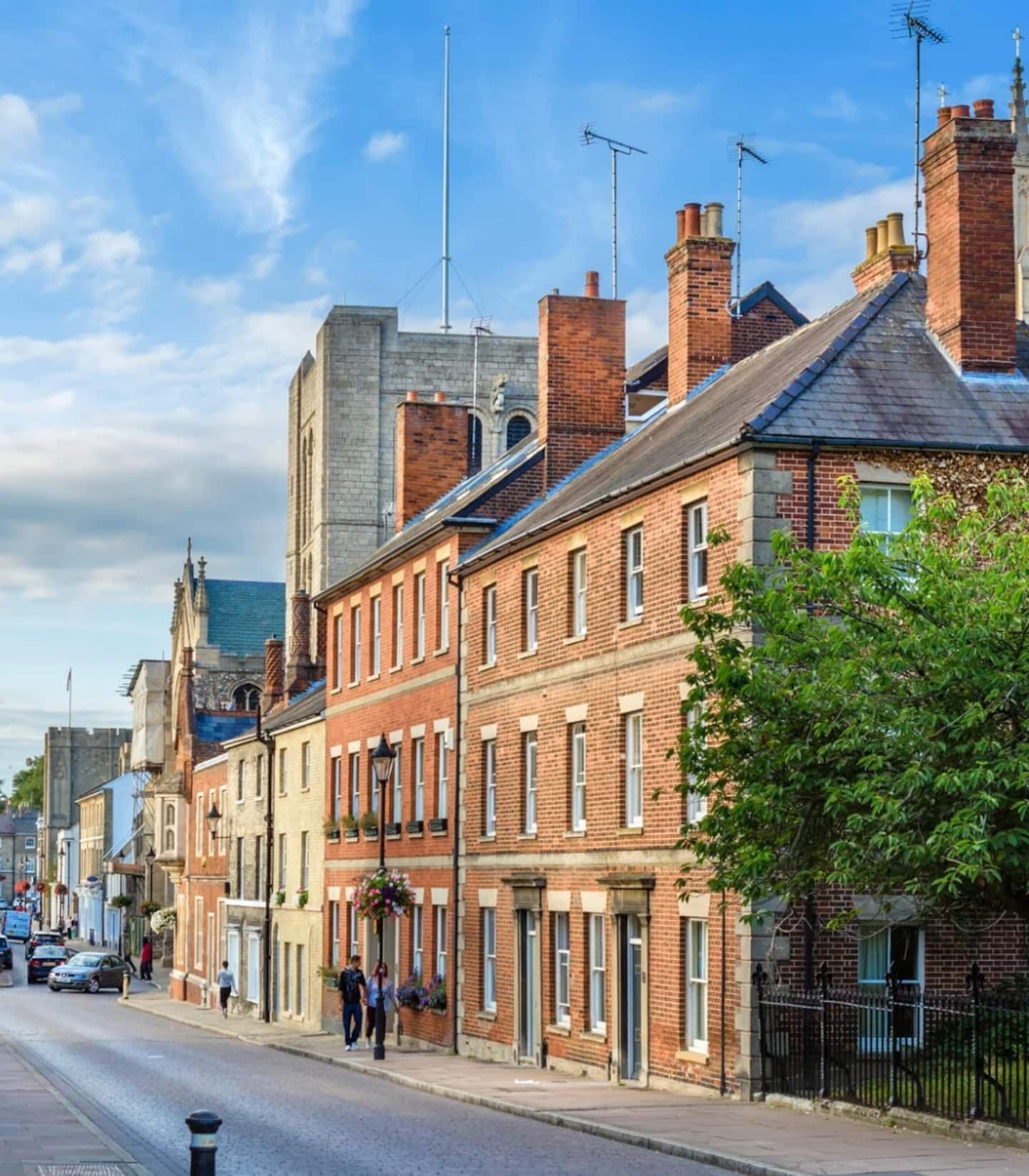A street with historic buildings, a clear sky, and a pedestrian.