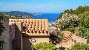 Un edificio costiero con tegole in terracotta, una scala in pietra e vista sul mare.