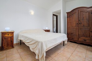Ein Schlafzimmer mit einem Bett, einem Nachttisch aus Holz, einem Kleiderschrank und einer Wandleuchte.