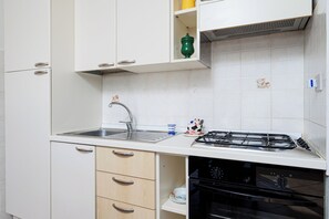 Eine Küche mit Spüle, Herd, Backofen und Schränken.