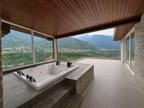 A spa area with a large bathtub and a view of a mountainous landscape. - The himalayan chester (Manali)