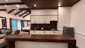 A modern kitchen with white cabinets, a wooden island, and a dining area with a sofa.